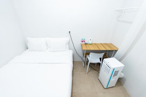 a small bedroom with a bed and a desk at The Hidden Khaosan เดอะ ฮิดเด้นข้าวสาร in Bang Bua Thong Railway Station
