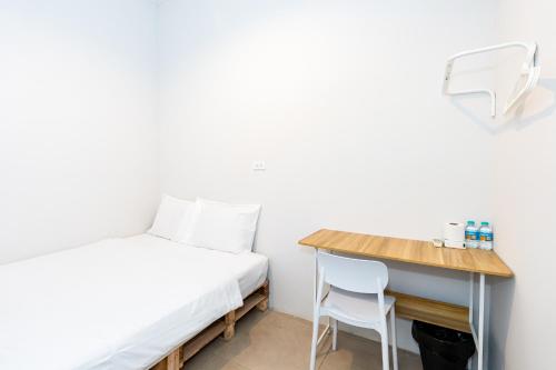 a small room with a bed and a desk at The Hidden Khaosan เดอะ ฮิดเด้นข้าวสาร in Bang Bua Thong Railway Station