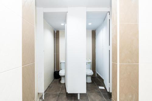 a bathroom with two toilets and two sinks at The Hidden Khaosan เดอะ ฮิดเด้นข้าวสาร in Bang Bua Thong Railway Station