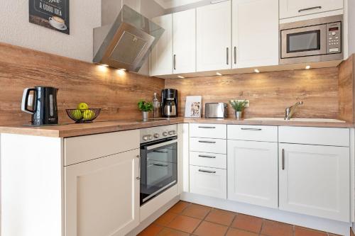 a white kitchen with white cabinets and a sink at Landhaus Pönitz am See Wohnung 7 in Klingberg