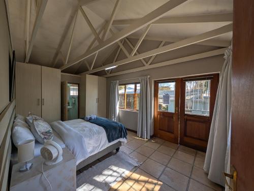 a bedroom with a bed in a room with windows at Oude Post Guesthouse and Cottage - The Old Postmaster's House in Lydenburg