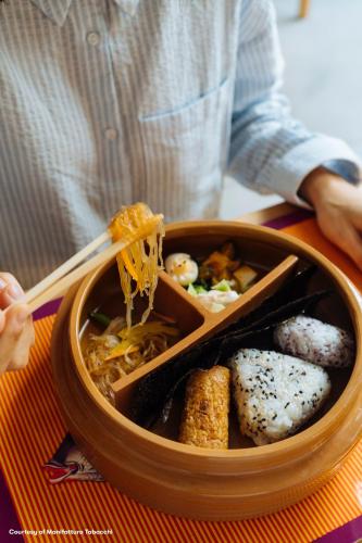 a person eating food with a bowl of noodles and sushi at NEW OPENING 2025 aparto Florence Manifattura in Florence