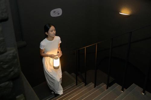 a woman is standing on stairs with a light at Cave Ryokan Hotel by Aank Sungshin Women's University in Seoul