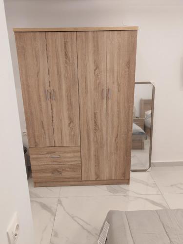 a wooden cabinet in a room with a mirror at Premium Studio Family I in Paralia Katerinis