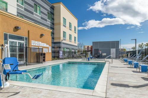 a swimming pool with chairs next to a building at Fairfield by Marriott Inn & Suites Winters Davis in Winters