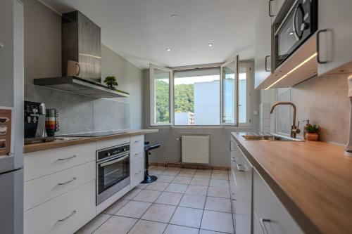 a kitchen with white cabinets and a large window at Le Fernand - Campus - Parking in Saint-Martin-dʼHères