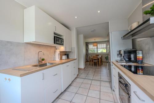 a kitchen with white cabinets and a tile floor at Le Fernand - Campus - Parking in Saint-Martin-dʼHères