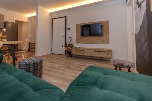 a living room with a green couch and a television at Ciesa Abete Rosso in Caprile