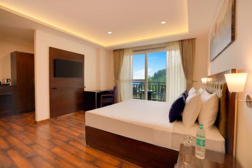 a hotel room with a bed and a balcony at Keys Select by Lemon Tree Hotels, Kufri, Shimla in Shimla