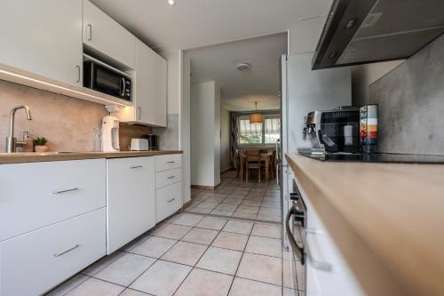 a kitchen with white cabinets and a tile floor at Le Fernand - Campus - Parking in Saint-Martin-dʼHères