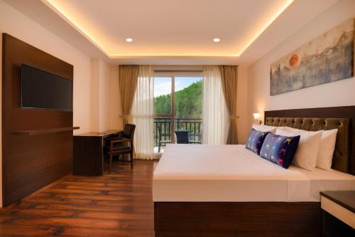 a bedroom with a bed and a desk and a television at Keys Select by Lemon Tree Hotels, Kufri, Shimla in Shimla
