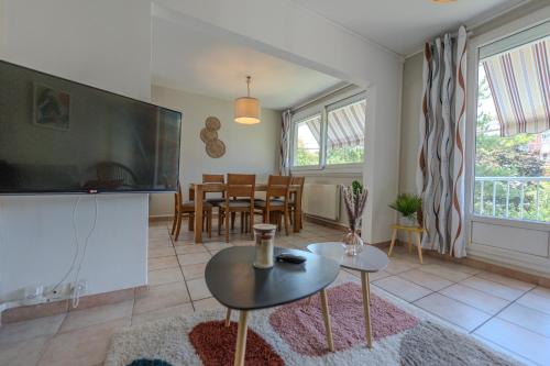 a living room with a large television and a table at Le Fernand - Campus - Parking in Saint-Martin-dʼHères