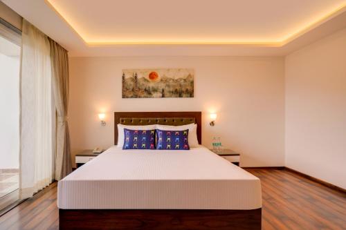 a bedroom with a large white bed with blue pillows at Keys Select by Lemon Tree Hotels, Kufri, Shimla in Shimla