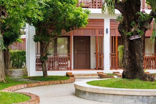 a house with a wooden door and trees at Rimping Village in Chiang Mai