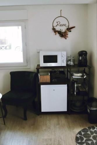 a living room with a microwave and a chair at Chambre indépendante avec salle de bain et toilettes in Romilly-sur-Andelle