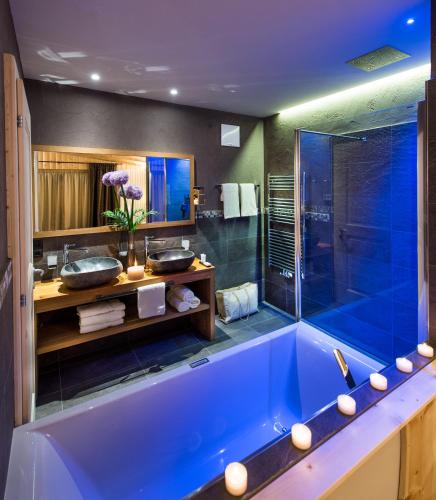 a bathroom with a blue tub and a shower at Hotel Santner Alpine Sport & Relax in Alpe di Siusi