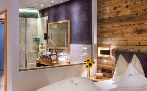 a bedroom with a bed and a bathroom with a sink at Hotel Santner Alpine Sport & Relax in Alpe di Siusi