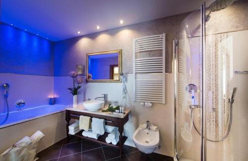 a blue bathroom with a sink and a shower at Hotel Santner Alpine Sport & Relax in Alpe di Siusi