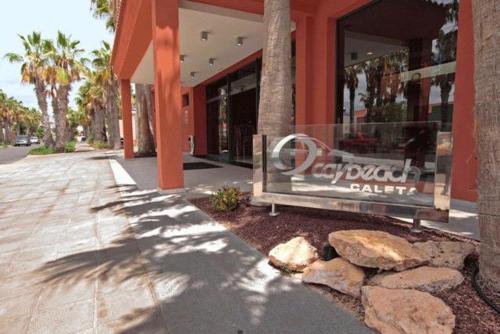 a building with a bench in front of a store at Caybeach Caleta in Caleta De Fuste