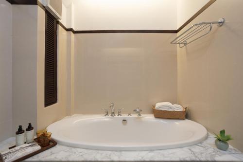 a bathroom with a large white tub in a room at Rimping Village in Chiang Mai