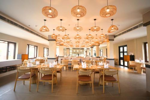 a dining room with tables and chairs and chandeliers at Vinaika Eco-Resort in Rānchī