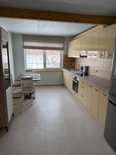 a kitchen with white cabinets and a table in it at Ronnenburg apartamenti in Rauna
