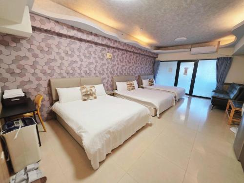 a hotel room with three beds and a couch at Yuanben Mountain Hot Spring Homestay in Jiaoxi