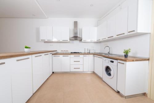 a white kitchen with white cabinets and a washer and dryer at Appartement Charmant à Hydra in Hydra