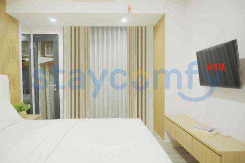 a bedroom with a white bed and a tv on the wall at Studio Pollux Habibie B1617 City View in Batam Center