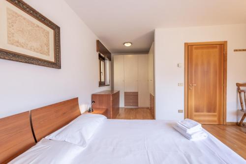 a bedroom with a white bed with a wooden headboard at Casa Cavina, ampia con giardino e garage in Venas