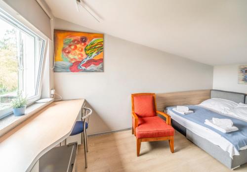 a bedroom with a bed and a chair and a window at Villa Art Korab in Gliwice