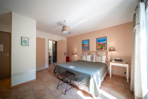 a bedroom with a bed and a table in a room at Hotel Les Ambres in Roussillon