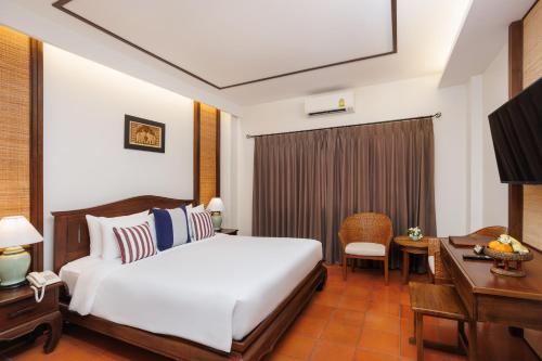 a hotel room with a bed and a desk and a television at Rimping Village in Chiang Mai