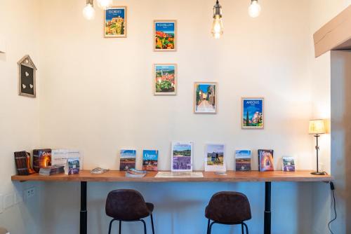 a table with two chairs and pictures on the wall at Hotel Les Ambres in Roussillon