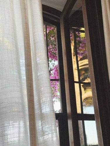 a window with white curtains and a stained glass at Agriturismo Casa Cometa in Principina a Mare