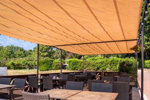 a patio with tables and chairs under a tent at Hotel Les Ambres in Roussillon