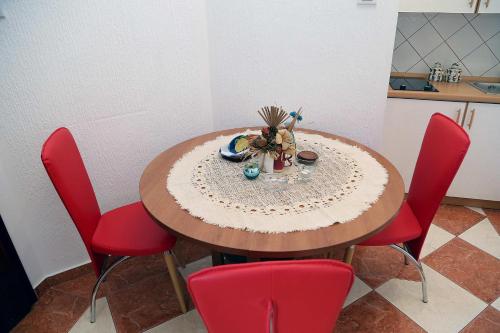 a dining room table with red chairs and a table with a centerpiece at Apartments Stevo Nikočević in Bar