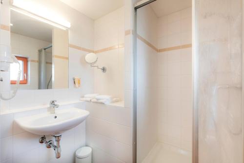 a white bathroom with a sink and a shower at JUFA Hotel Stubenbergsee in Stubenberg