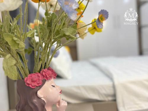 a doll head with a vase filled with flowers at Magaly Apartment & Hotel in Hai Phong
