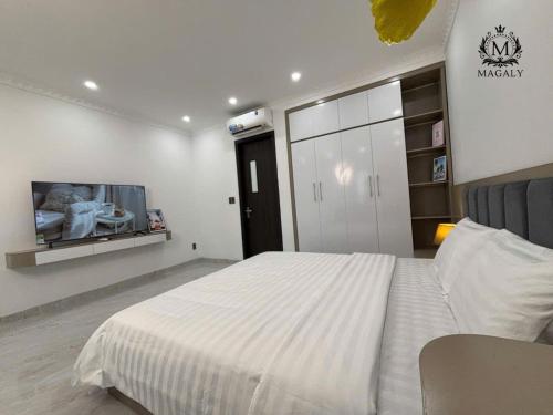 a bedroom with a white bed and a tv at Magaly Apartment & Hotel in Hai Phong