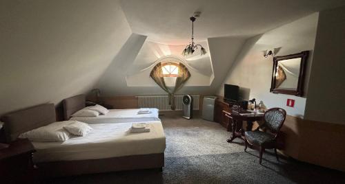 a bedroom with two beds and a desk and a window at Hotel Pałacyk Konin in Konin