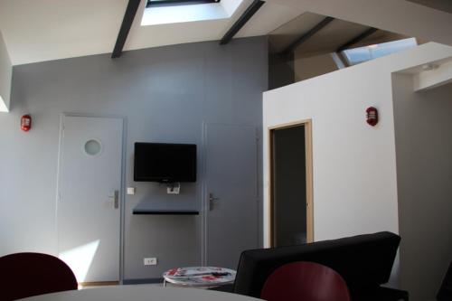 une pièce avec une table et une télévision sur un mur dans l'établissement 40m All Comfort In Front Of The Old Port, à La Rochelle