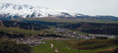 a town in a valley with a snow covered mountain at Syrgak in Dzhergalan
