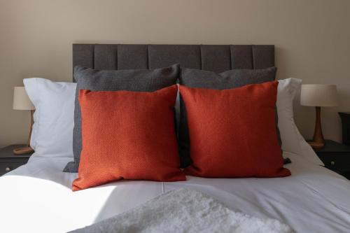 a bed with three red pillows on top of it at Dolfor in Menai Bridge