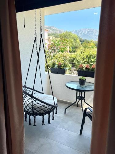 eine Veranda mit einer Schaukel und einem Tisch auf dem Balkon in der Unterkunft Danin apartmani in Bar