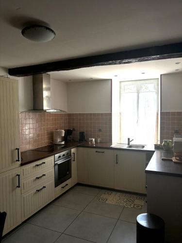 une cuisine avec des armoires blanches, un évier et une fenêtre dans l'établissement La Maison d'Amélie, à Saint-Fort-sur-Gironde