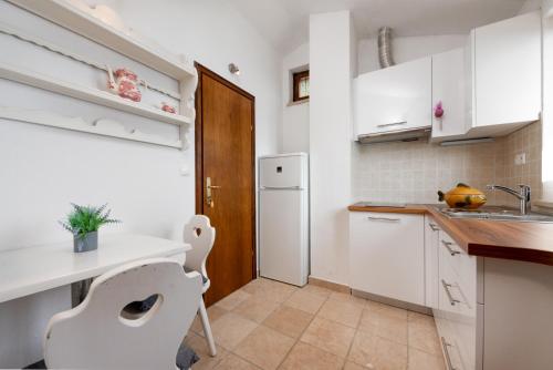 a kitchen with white cabinets and a white refrigerator at Apartments with pool Maraska in Brela