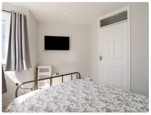 a white bedroom with a bed and a television at The Alex in London