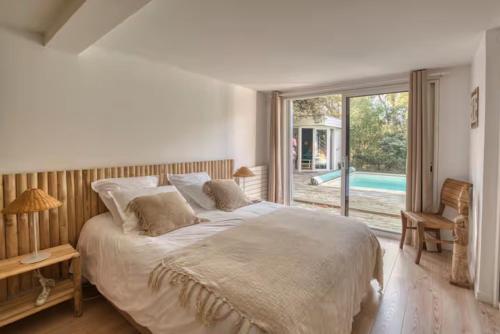 a bedroom with a large bed and a large window at Calme absolu détente en famille & Piscine chauffée in La Tremblade