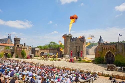 une grande foule de personnes assises devant un château dans l'établissement PUY DU FOU 5p 820FG, à La Boissière-de-Montaigu
